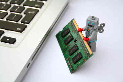 Hero picture: A tiny robot holding a RAM card in its hands while standing next to a Apple Macbook.